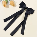 Primer plano de un elegante lazo de pelo en satén negro con cintas largas sobre fondo beige - Negro