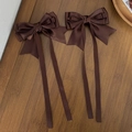 Detail of dark brown satin ribbon bow hair clips with elegant long streamers on wood - Brown