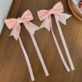 Close-up of pink satin bow hair clips with long ribbons on a textured wood background - Flesh Pink