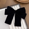 Close-up of a large black velvet bow hair clip with ribbons on a jewelry display tray - Black