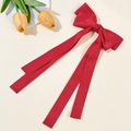 Detalle de pinza para pelo con lazo de satén rojo y cintas largas en fondo beige - Rojo