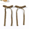 Close-up of two brown knitted bow hair clips with long ribbons and metal duckbill clips - Caramel color