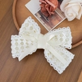 Detailed macro shot of the cream white lace bow hair clip showing intricate floral patterns - Beige