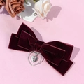 Detail der Samt-Schleifen-Haarspange mit silbernem Herz-Kreuz-Anhänger auf Pink - Burgunderrot