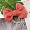 Close-up of coral red lace mesh bow headband for babies on a natural wood background - Watermelon red