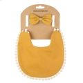 Close-up of mustard yellow boho baby bib with white pom-pom trim and matching bow headband - Turmeric