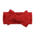 Detailed close-up of bright red ribbed knit baby headband with a large soft bow decoration - Red