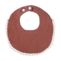 Detail of rust red cotton gauze baby bib with white pom-pom trim and snap buttons - Coffee