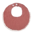 Detail view of terracotta cotton muslin baby bib with white pom-pom trim and snap buttons - Dark Korean Pink