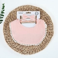 Detail of pink muslin baby bib with pom-pom trim and matching bow headbands - Snow Bud