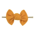 Close-up of mustard yellow waffle fabric bow and soft nylon headband for infants - Ginger Yellow