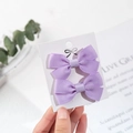 Nahaufnahme von zwei hellvioletten Ripsband-Schleifen-Haarspangen für Babys auf einer Karte - Schleife Seitenclips / Hellviolett