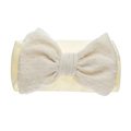 Gros plan d'un bandeau bébé en nylon beige avec un nœud doux à texture à pois suisses - Beige