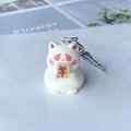 Macro detail of white flocked cat keychain with coin eyes and gold currency plaque - Money Cat