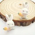 Detail of white flocked rabbit earrings with orange carrot on a rustic wood slice - Fluffy Radish Rabbit