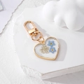 Heart-shaped gold alloy keychain with blue dried flowers in clear resin on stone - Blue Flower Keychain