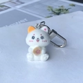 Close-up of white flocked cat plush keychain holding a strawberry doughnut charm - Prosperity Cat