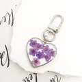 Macro shot of heart-shaped pendant with purple dried flowers and silver lobster clasp - Purple