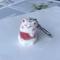 Detailed close-up of white flocked fortune cat keychain with red fish charm and silver clasp - Koi Fish Cat