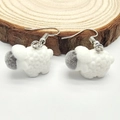 Macro detail of cute white flocked sheep earrings on a rustic natural wood surface - Fluffy Sheep