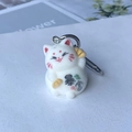 Macro detail of a white flocked lucky cat keychain with Baofu text and silver hook - Get Rich Cat