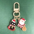 Close-up of enamel Christmas keychains featuring a cute black cat and Santa Claus charms - Candle Black Cat and Santa Claus