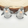 Cute flocked penguin drop earrings with classic grey and white finish on a wooden stand - Plush Penguin