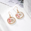 Détail de boucles d'oreilles en résine avec de vraies fleurs séchées et cadres dorés - Fleur Rose