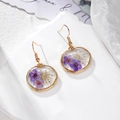 Gros plan détaillé de boucles d'oreilles dorées avec fleurs séchées en pendentifs - Fleur Violette