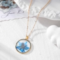 Handmade gold chain necklace with a blue dried flower pendant in clear resin - Blue Floral Necklace