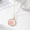 Close-up of golden necklace with a round pendant featuring a real pink dried flower - Pink Floral Necklace