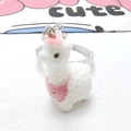 Dettaglio macro di un simpatico portachiavi a forma di alpaca bianco con bavaglio rosa - Alpaca con Bavaglino Rosa