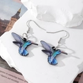 Dettaglio di orecchini a forma di colibrì in acrilico colorato su base in pietra bianca - Uccello Blu