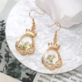 Close-up of golden crown earrings with white dried flowers in resin drop pendants - Crown White Flower