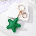 Portachiavi stella minimalista in pelle verde con hardware dorato su un piedistallo bianco - Stella a Cinque Punte (K187) / Ciano