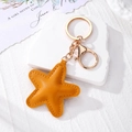 Detail of ginger yellow star leather keychain with fine stitching and gold metal clasp - Orange