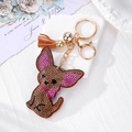 Détail du porte-clés chien en strass avec attaches dorées et pompon en cuir orange - Chien marron à grandes oreilles