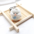 Close-up of cute white flocked chick keychain holding a blue heart on a bamboo tray - Flocked Duck with Shovel