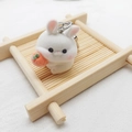 Close-up of white flocked rabbit keychain with orange fruit detail on bamboo tray - Flocking Carrot Rabbit