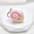 Detail of pink flocked snail keychain with silver metal ring on white geometric stand - Flocking Little Snail