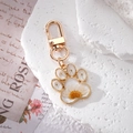 Macro detail of cat paw keychain with real daisy flowers and gold resin frame - White Flower Cat Paw