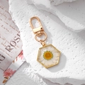 Close-up of hexagonal gold keychain featuring real white daisy pressed in clear resin - White Daisy Hexagon