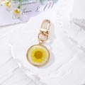 Detail of luminous round resin keychain with real yellow dried daisy flower and gold clasp - Yellow Daisy