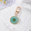 Detail of luminous gold resin keychain with real dried blue daisy flower and metal ring - Blue Daisy