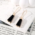 Boucles d'oreilles dorées élégantes avec gouttes de cristal noir trapèze sur fond blanc - Noir