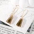 Gros plan de boucles d'oreilles trapèze avec cristal gris fumé et crochets dorés - Marron