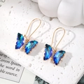 Detailed close-up of butterfly earrings with blue gradient crystals and gold plating - Sapphire Blue