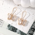 Macro detail of elegant gold butterfly drop earrings with clear crystals and long hooks - Clear