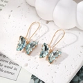 Macro detail of butterfly ear hooks with light blue crystals and gold-plated alloy - Transparent Blue