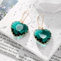 Detalle de pendientes de cristal verde esmeralda con forma de corazón y gancho dorado - Azul lago